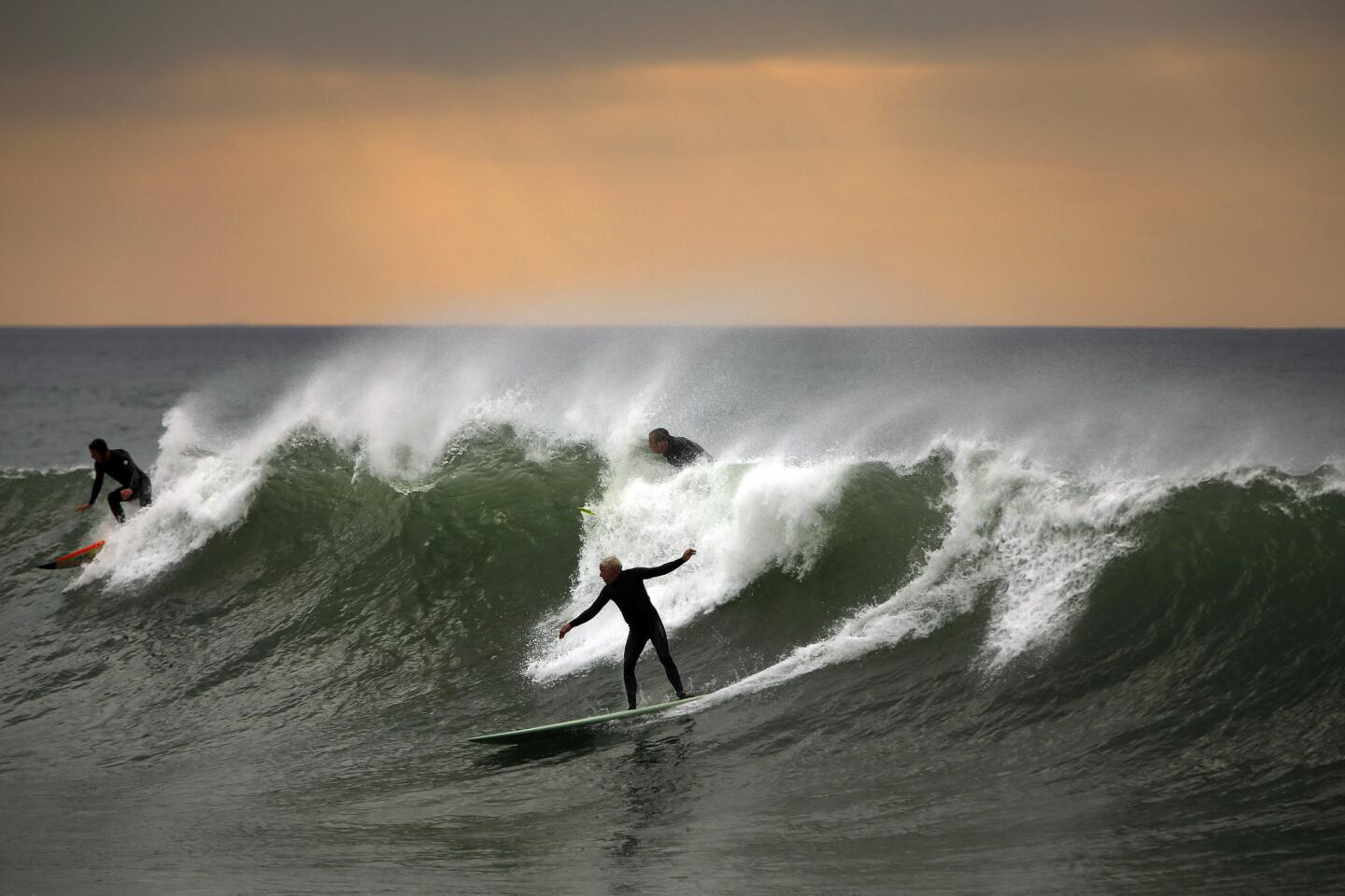 Tom Muneio, 61, of Santa Barbara, center, enjoys a wave in Ventura County, where sets of 8 to 10 feet pounded the coast ahead of rain storms expected late Thursday afternoon.