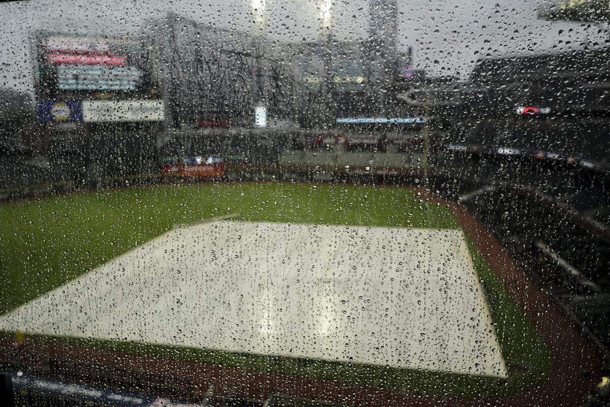 Rain hits a window overlooking Truist Park before Game 2 of baseball's National League Division Series between the Atlanta Braves and the Philadelphia Phillies, Wednesday, Oct. 12, 2022, in Atlanta. The game has been rain delayed. (AP Photo/John Bazemore)