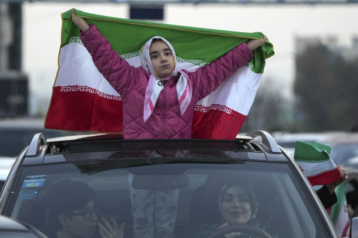 İran'ın Galler'e karşı kazandığı zaferin ardından Tahran'da bir sokak kutlaması sırasında bir kız ülkesinin bayrağını kaldırıyor.