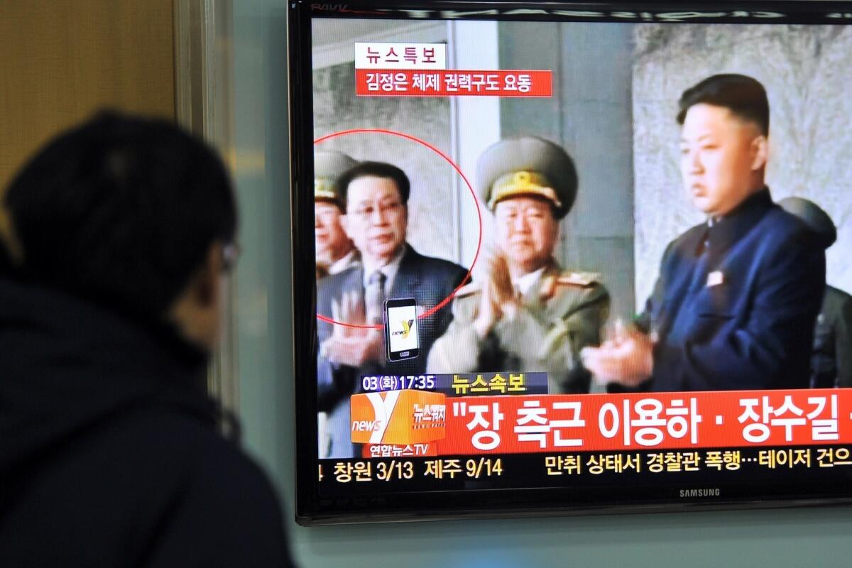 A television at a train station in Seoul shows a news program reporting the apparent ouster of Jang Song Taek (circled), the uncle of North Korean leader Kim Jong Un (right).