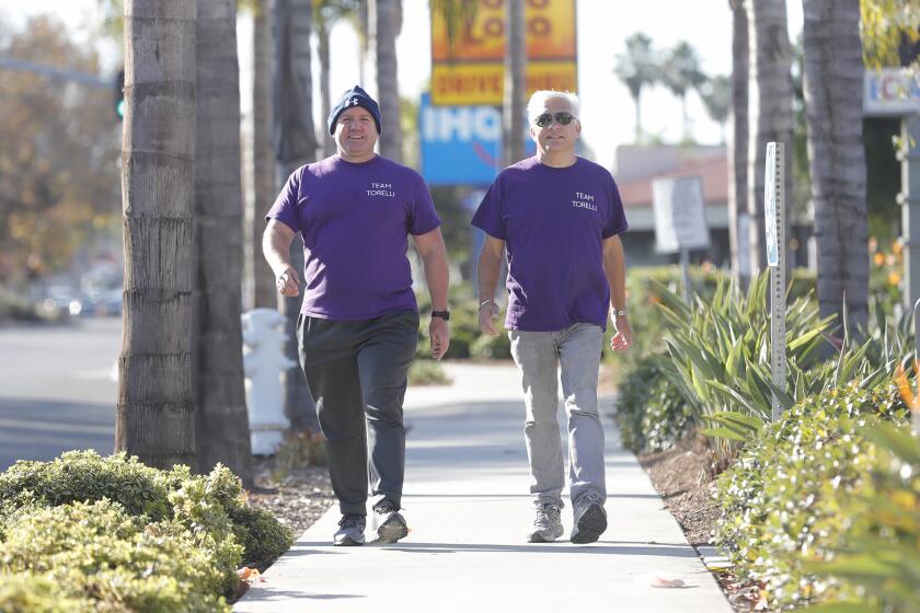 Matt Weich and Danny Wexler, from left, walk up Harbor Blvd in Costa Mesa on Monday. Weich and Wexler are embarking on a 45-mile, 100,000 step Olympian Sandal FitBit challenge as a charity effort for WISEPlace, an OC nonprofit that aims to combat homelessness for women.
