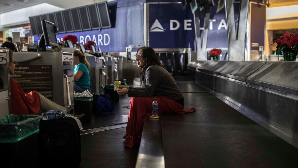 A passenger sits behind a ticket counter inside a darkened Hartfield-Jackson Atlanta International Airport on Sunday,