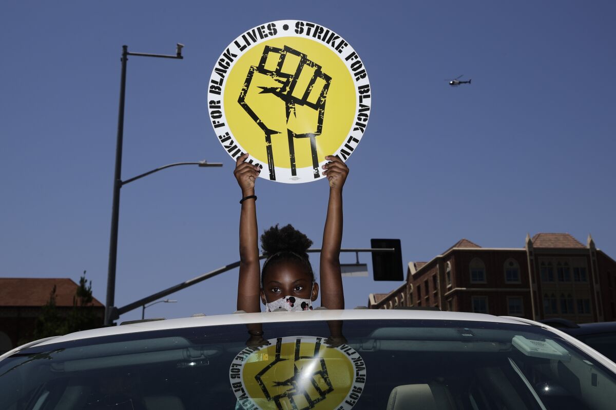 An 8-year-old girl holds up a sing through the sunroof of a car during a rally in Los Angeles.