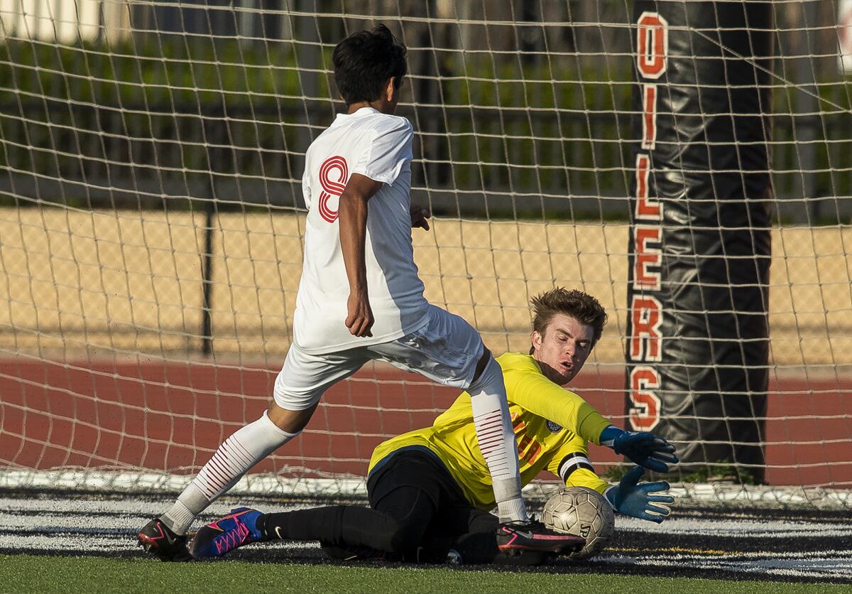 Huntington Beach's Daniel Kotkosky saves a goal against Estancia's Hector Garcia in a Division 2 boys' soccer playoff game.