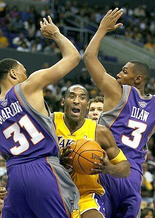 Laker Kobe Bryant squeezes by Suns Shawn Marion and Boris Diaw.