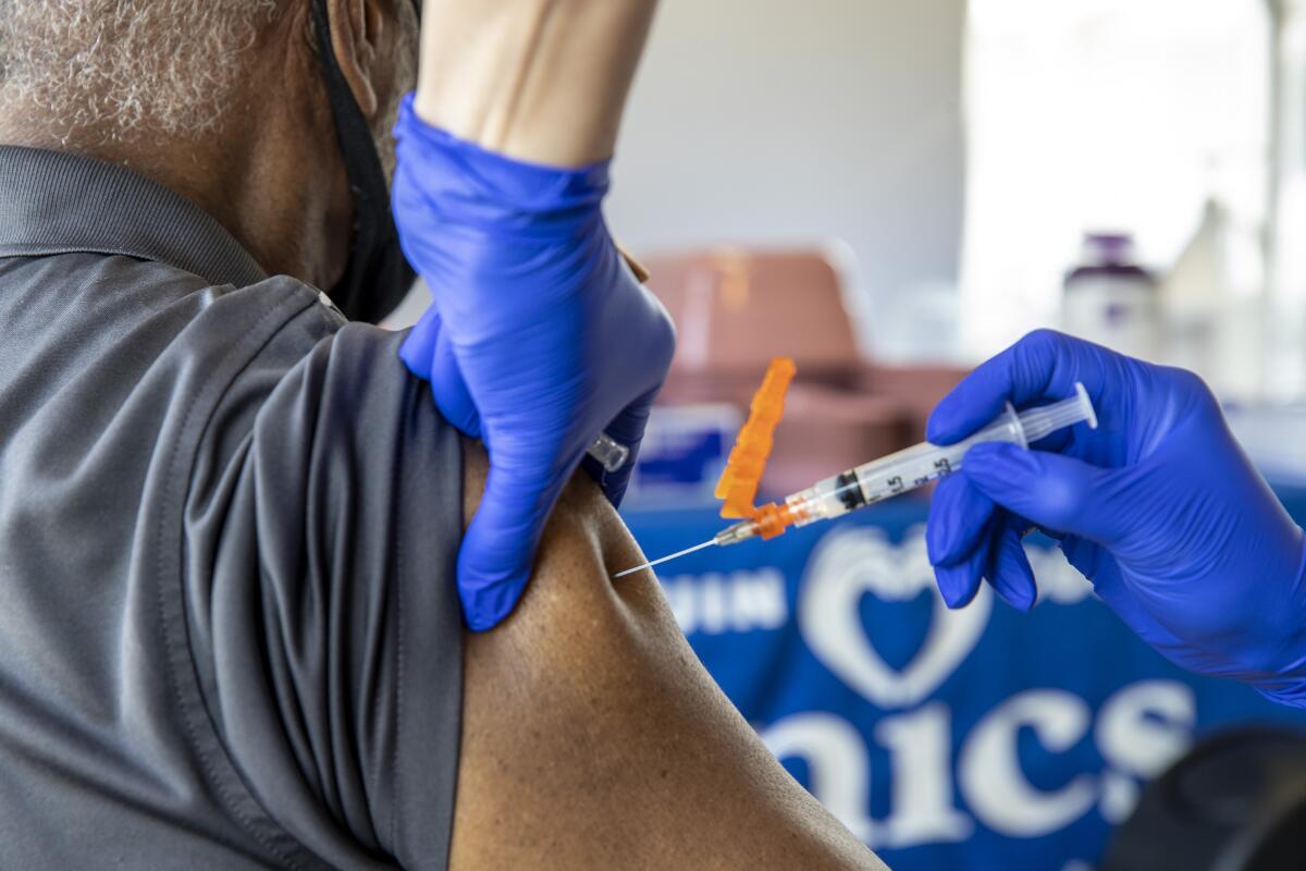 Closeup of gloved hands injecting vaccine into a man's upper arm