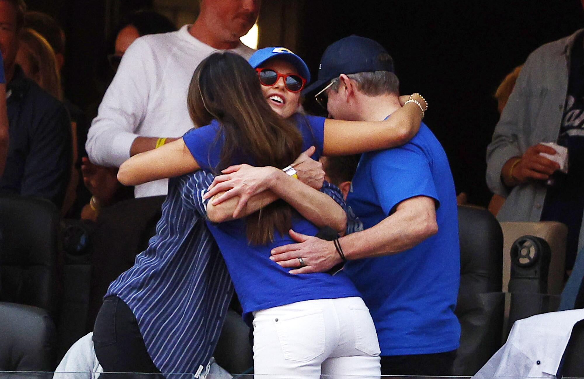 Two women and a man have a group hug.
