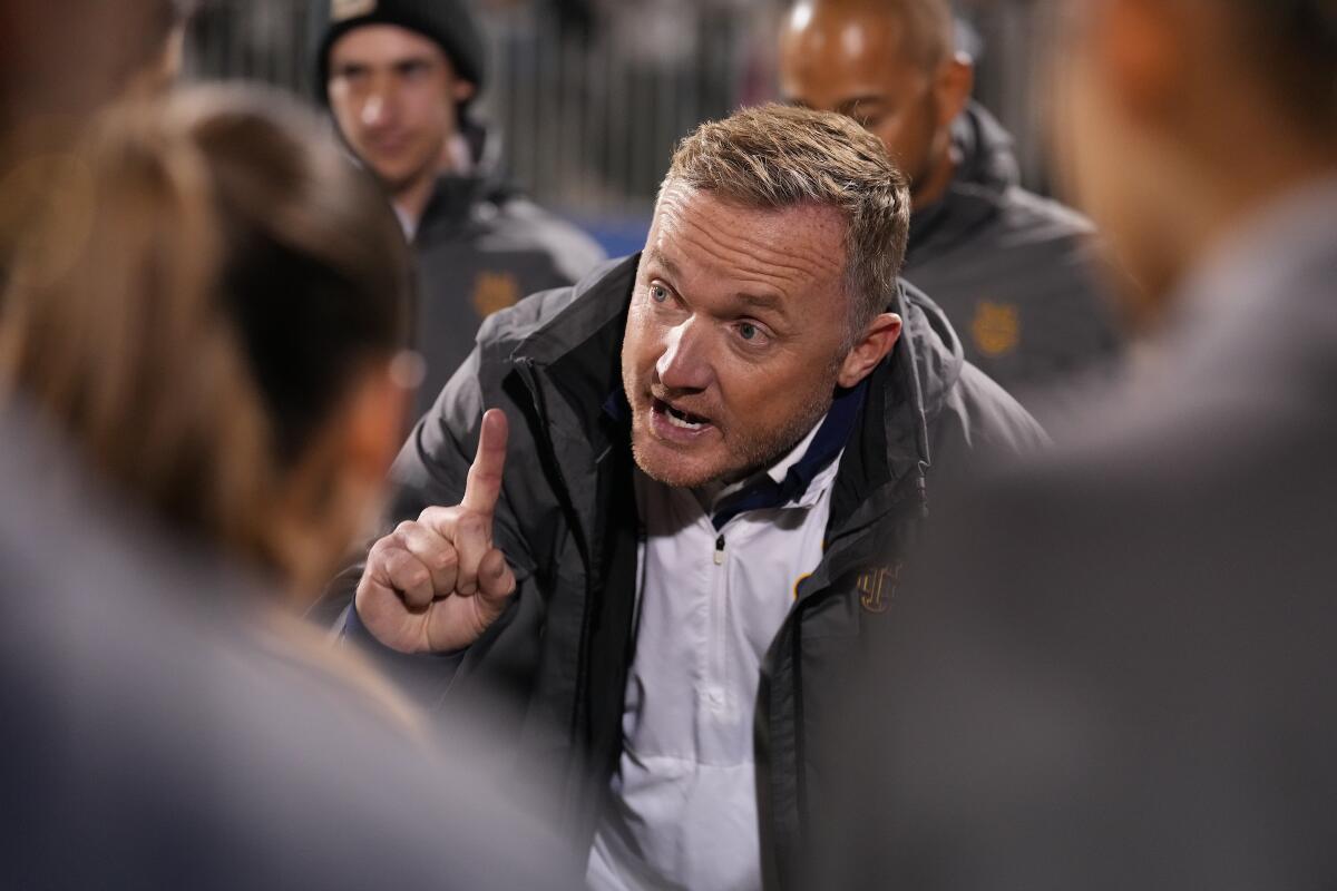 Scott Juniper, entraîneur de football féminin de l'UC Irvine, parle à ses joueuses lors d'un match.