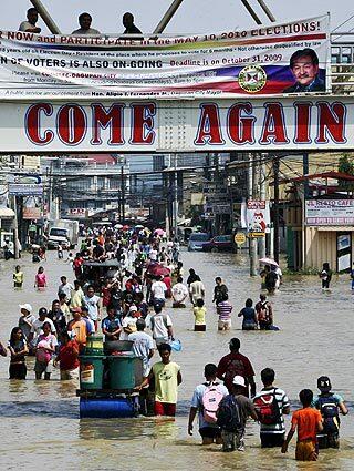 Residents wade through flood waters as they go on with their daily business in Dagupan City, in Pangasinan province north of Manila. Rescuers struggled through mud Saturday to clear mountain roads after dozens of landslides buried villages and cut off towns in the rain-soaked northern Philippines.