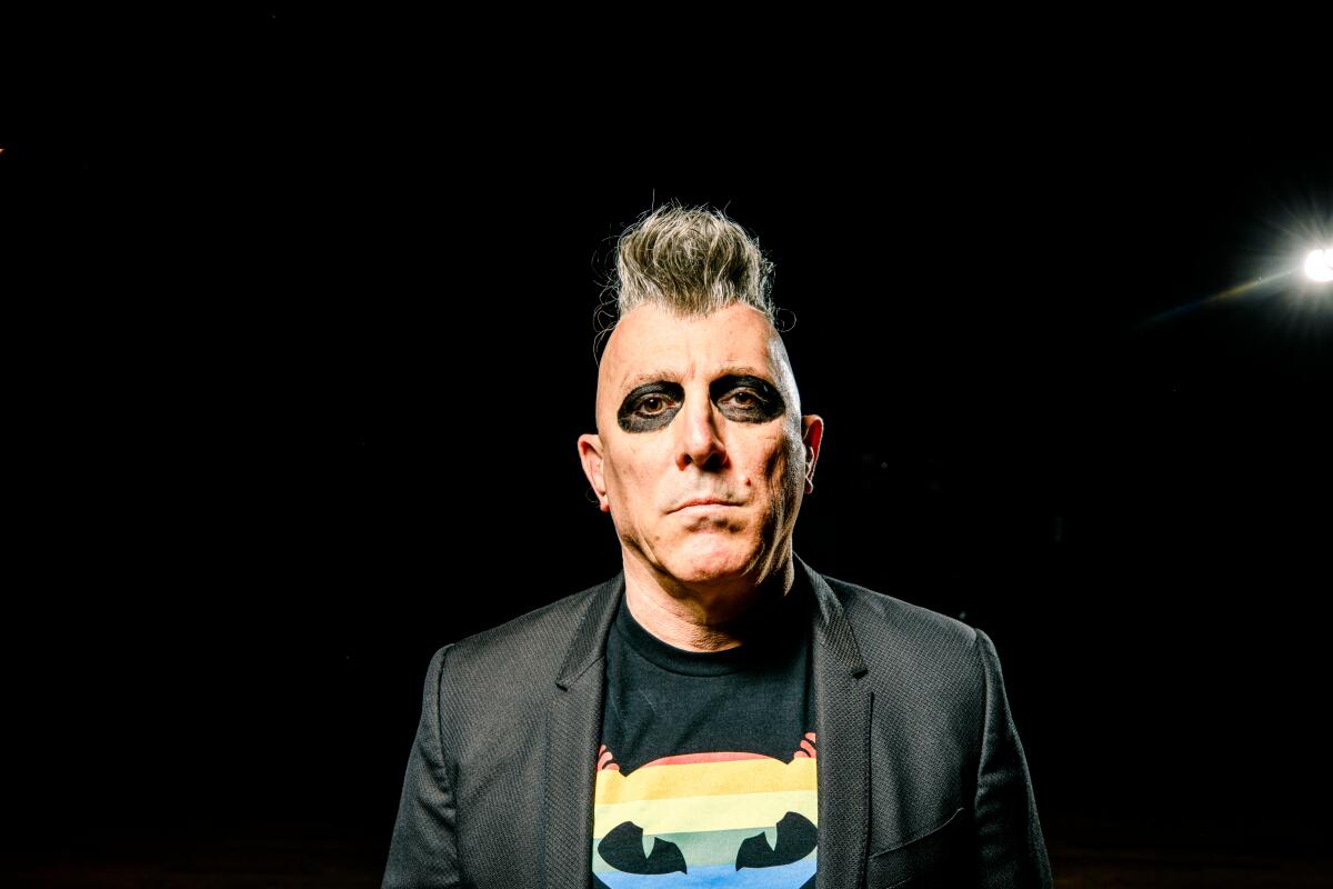 Man with mohawk and black eye paint standing in front of black background