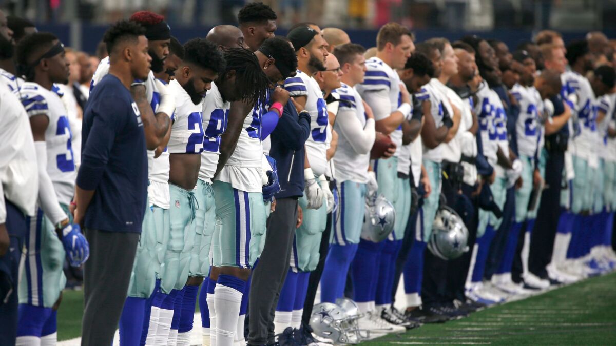 The Dallas Cowboys and staff stand on the sideline during the playing of the national anthem before their game against the Green Bay Packers on Oct. 8.
