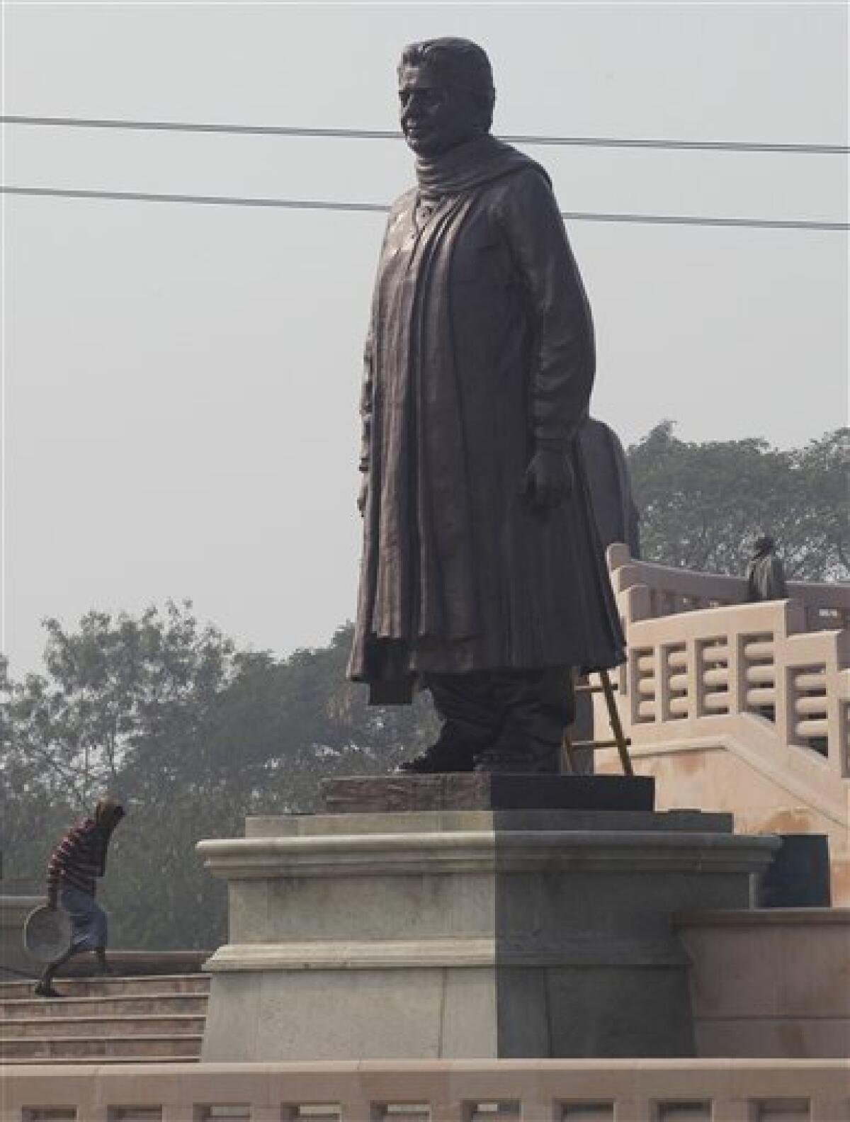 A worker walks by a statue of the Chief Minister of Uttar Pradesh, Mayawati, at a park in Noida, Uttar Pradesh, India, Monday, Jan. 9, 2012. Workmen carting truckloads of cloth raced Monday to comply with election regulations and cover up a dozen gigantic statues that a flamboyant Indian chief minister had erected of herself. India's Election Commission said the massive statues of Mayawati, who uses one name and is a hero to the country's lowest castes, were built using public money and their display violated the rules for next month's election in her Uttar Pradesh state. (AP Photo/Saurabh Das)