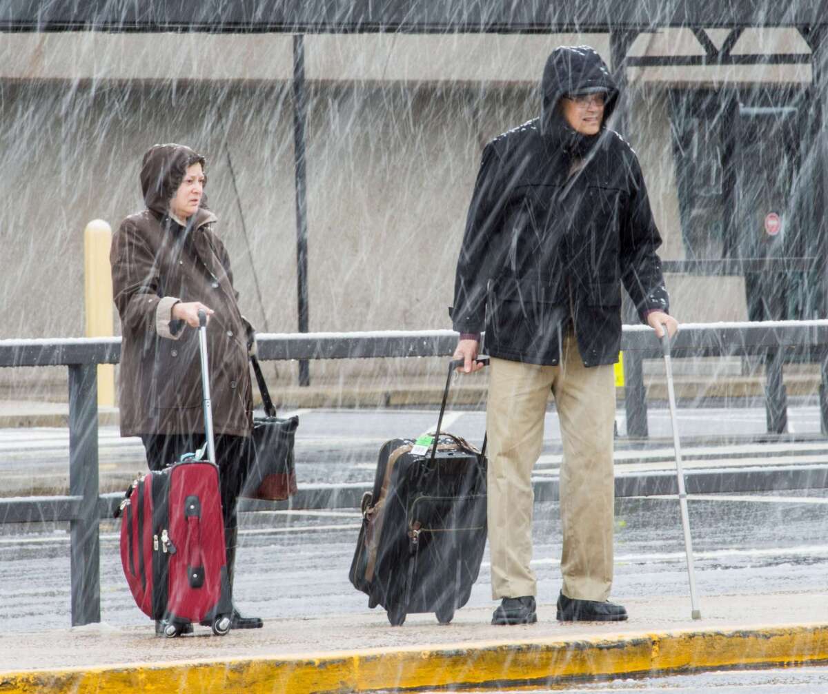 Passengers at Dulles International Airport outside Washington arrive to snow showers Wednesday on the busiest travel day of the year.