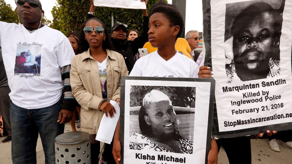 David Michael, left, father of Kisha Michael, his daughter Trisha Michael, and Kisha's son, Mikel Nicholson, 12, join community members in February at the site where Kisha Michael and Marquintan Sandlin were shot and killed by Inglewood police.