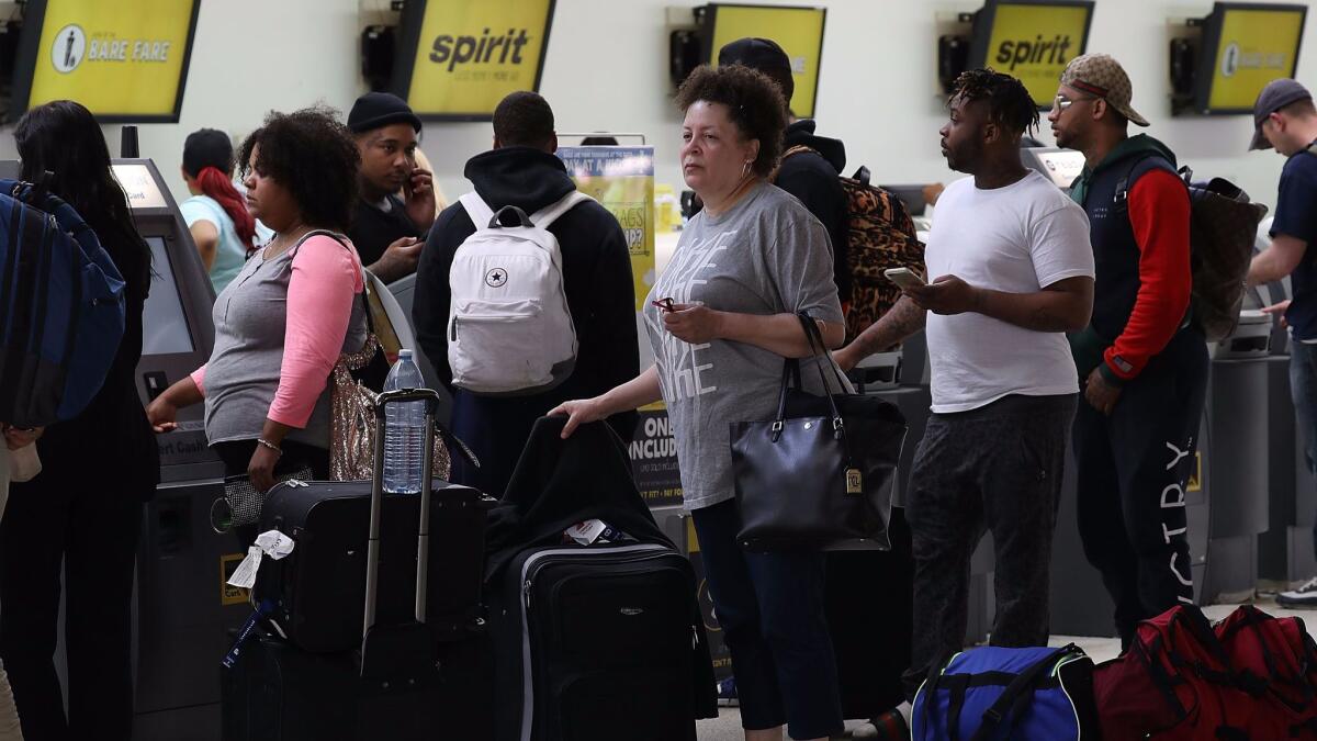 People stand in line to check in at the Spirit Airlines counter at the Fort Lauderdale-Hollywood International Airport. A chaotic scene erupted May 8 at the Spirit Airlines counter after flights were canceled.