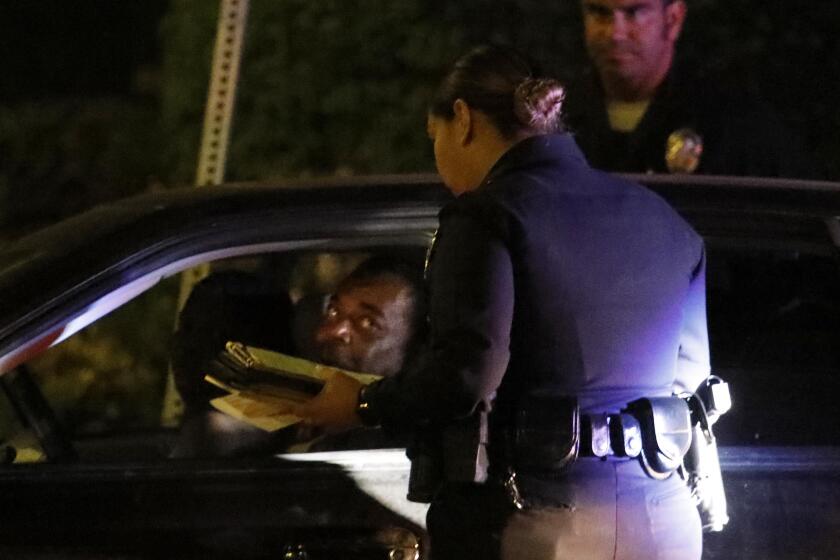 LOS ANGELES, CA - JULY 25, 2019 - - L.A.P.D. officers give a man a ticket for an expired registration in South Los Angeles on July 25, 2019. (Genaro Molina / Los Angeles Times)
