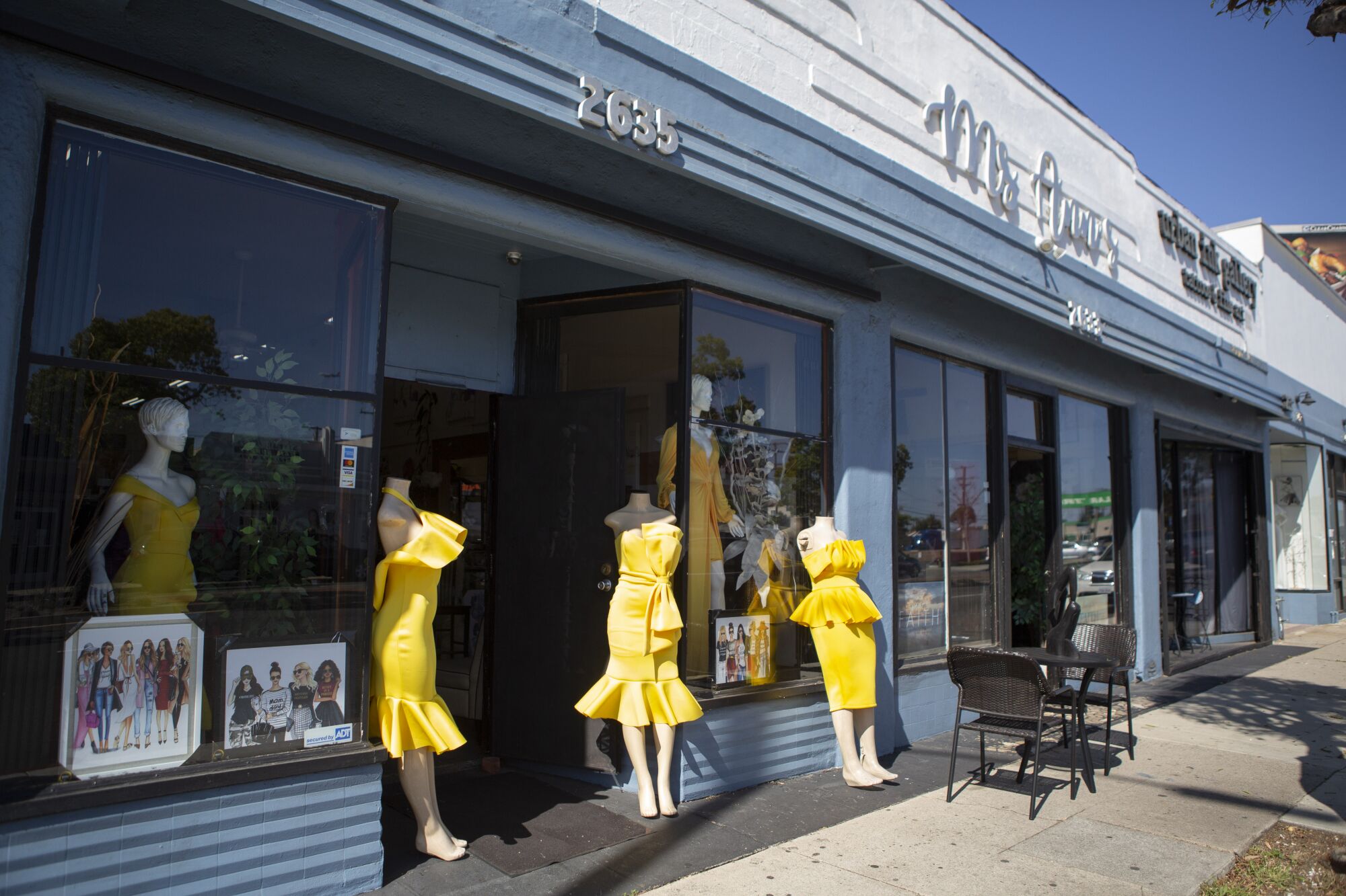Mannequins in yellow dresses in the window of a storefront and on the sidewalk near the door