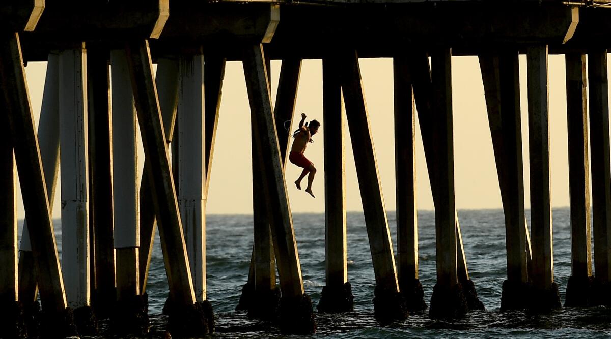 A lifeguard jumps into the water from Hermosa Beach Pier as part of a rescue demonstration.