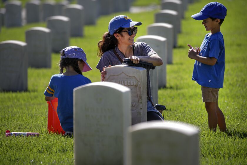 Los Angeles, CA - September 24: A UNCLA alumni Jackie Toenniessen, 36, center, brought her children Isabelle, 8, left, and Nicolas, 4, Los Angeles National Cemetery to on clean veterans' headstones on Saturday, Sept. 24, 2022 in Los Angeles, CA. (Irfan Khan / Los Angeles Times)