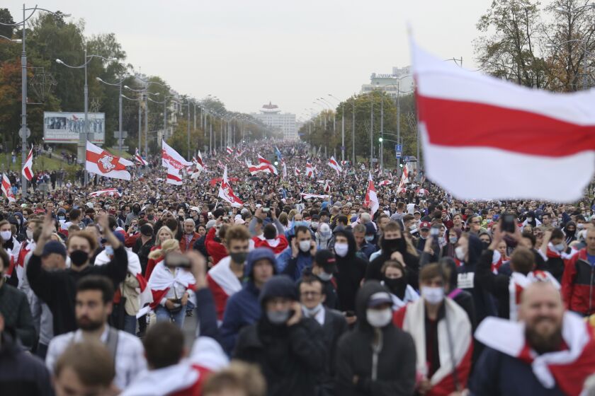 People with old Belarusian national flags march during an opposition rally to protest the official presidential election results in Minsk, Belarus, Sunday, Sept. 27, 2020. Hundreds of thousands of Belarusians have been protesting daily since the Aug. 9 presidential election. (AP Photo/TUT.by)