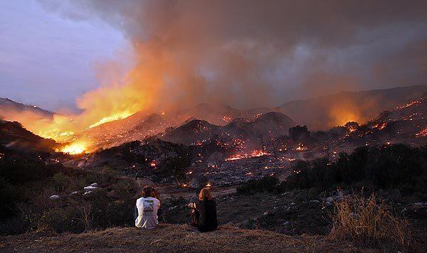 Sunland residents Michael and Susan Schaafsma watch the hills near their home burn at twilight on Tuesday.