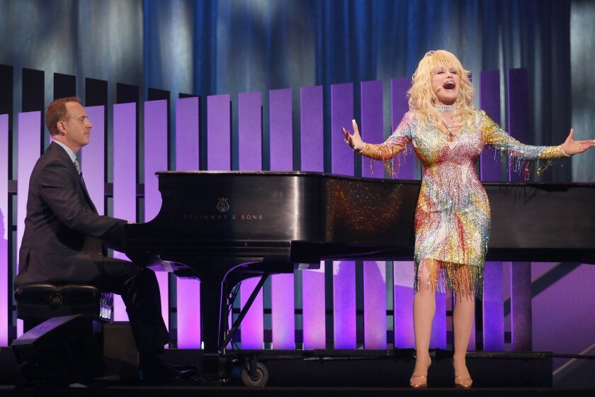 Singer Dolly Parton, right, performs as Robert Greenblatt, Chairman NBC Entertainment, accompanies on piano during the 2015 NBC Upfront Presentation in New York.