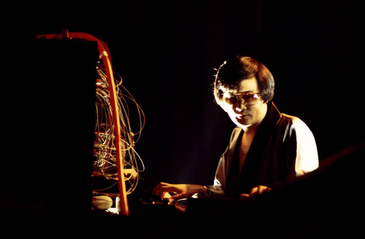Isao Tomita performing on a synthesizer, as patch cords dangle above the keyboard. (Getty)