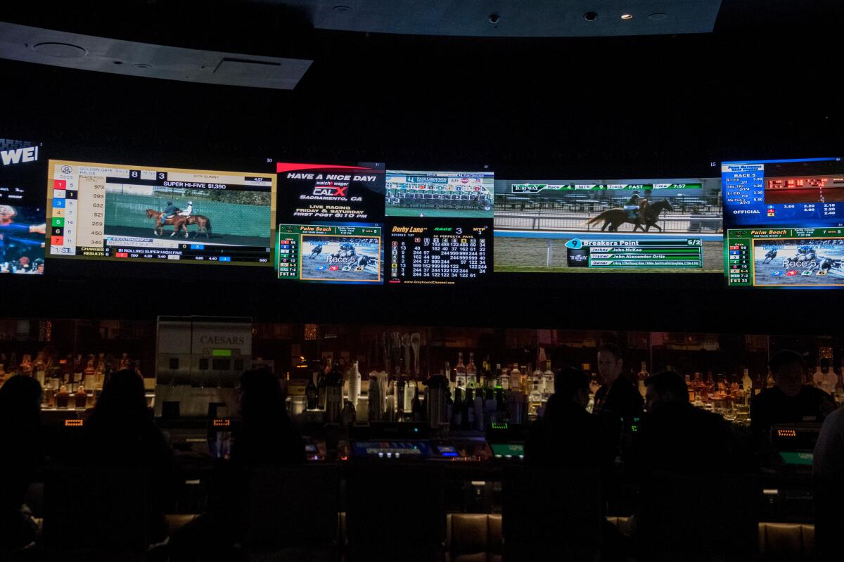 Horse racing is on display at a sports book at Caesars Palace Hotel and Casino in Las Vegas on March 13, 2020.