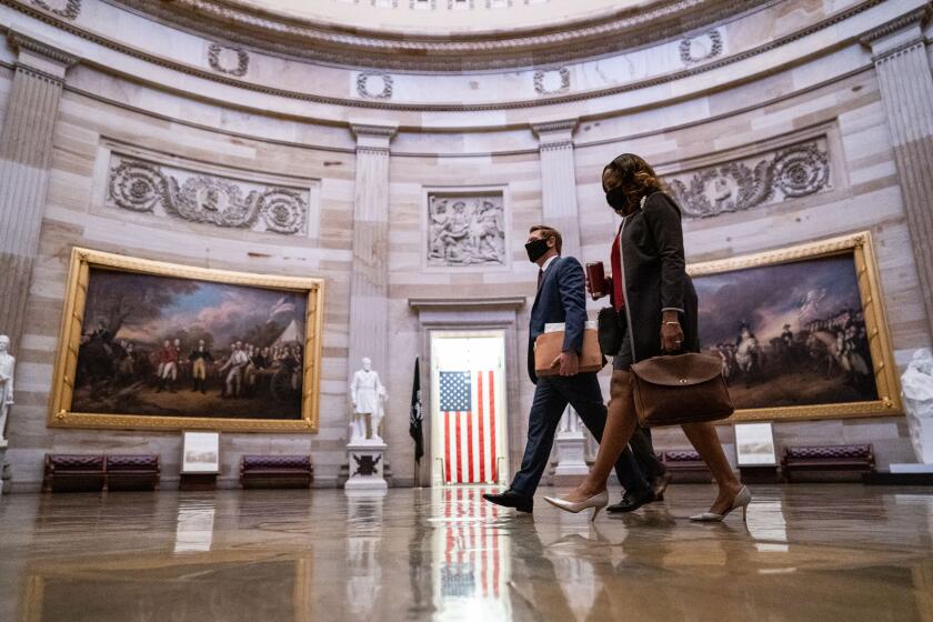 WASHINGTON, DC - FEBRUARY 09: Impeachment manager Rep. Eric Swalwell and Rep. Stacey Plaskett (D-VI) walk through the Rotunda of the U.S. Capitol Building on Tuesday, Feb. 9, 2021 in Washington, DC. The Senate begins the second impeachment trial of former President Donald Trump today, Feb. 9. (Kent Nishimura / Los Angeles Times)