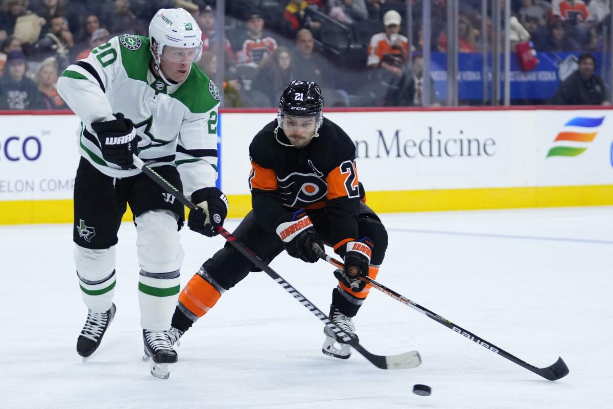 Dallas Stars' Ryan Suter, left, tries to clear the puck away from Philadelphia Flyers' Scott Laughton during the second period of an NHL hockey game, Sunday, Nov. 13, 2022, in Philadelphia. (AP Photo/Matt Slocum)