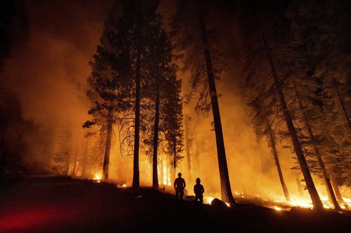Cal Fire Capts. Derek Leong, right, and Tristan Gale monitor a firing operation, where crews set a ground fire to stop a wildfire from spreading, while battling the Dixie Fire in Lassen National Forest, Calif., on Monday, July 26, 2021. (AP Photo/Noah Berger)