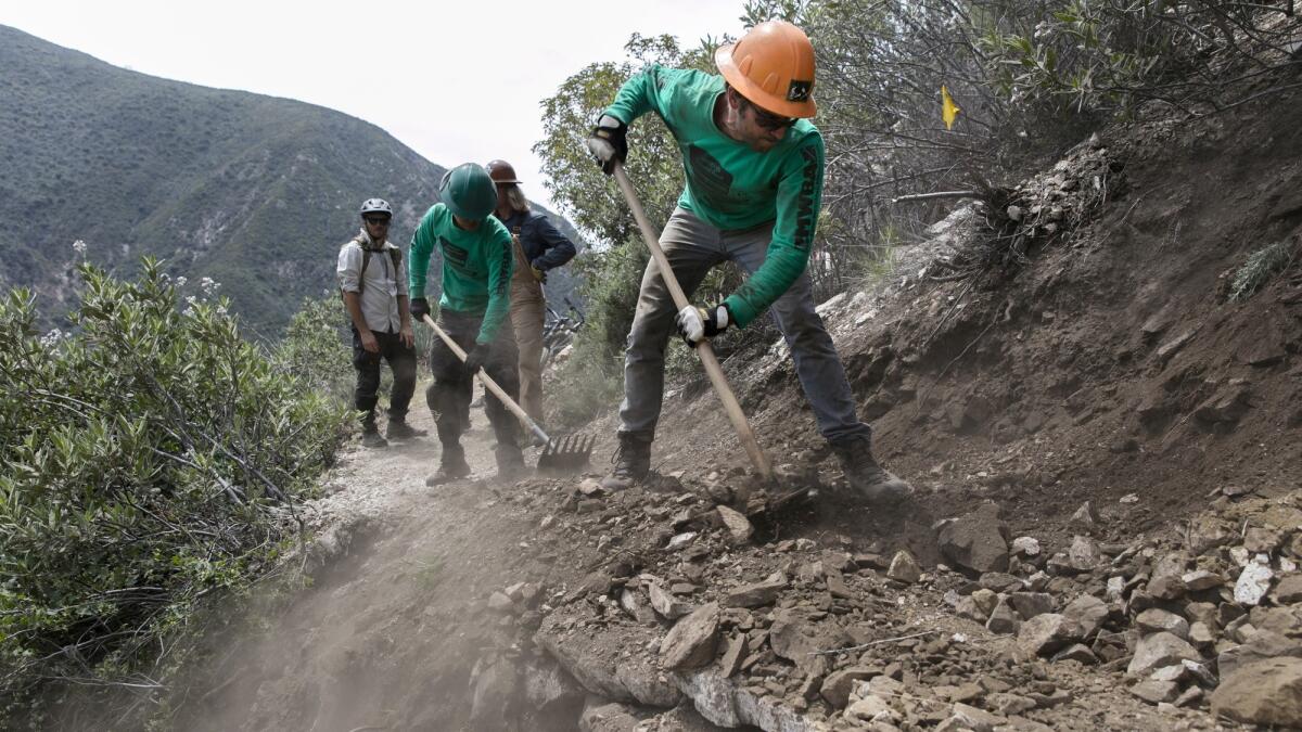 Brad Moore, 29, works on filling in the path along damaged sections of the Gabrielino Trail.