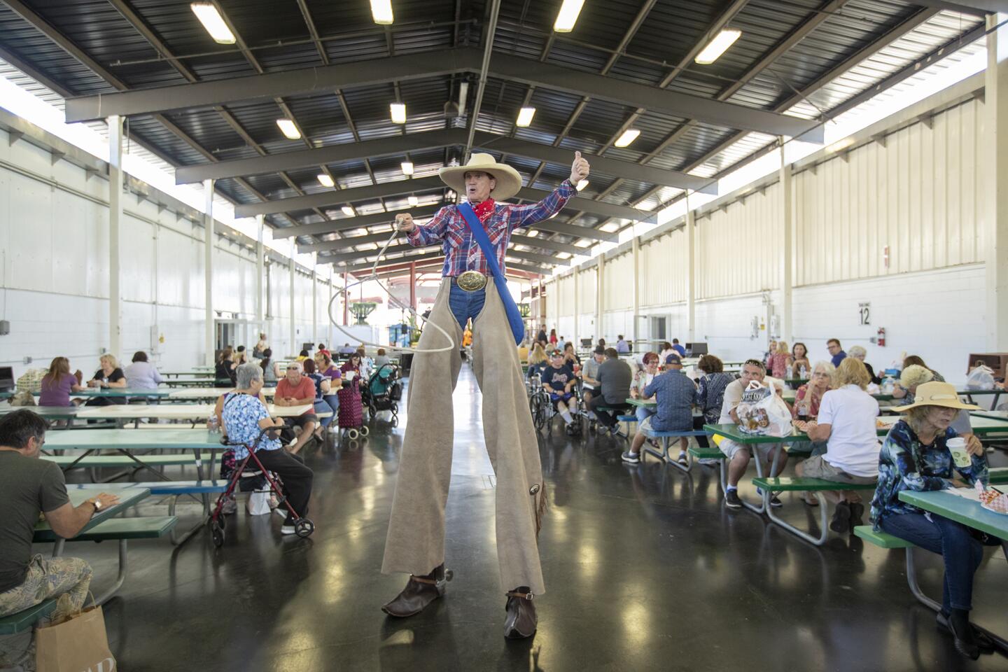 Bill Witter, performing as WC Willy, stilt-walks at the Harvest Festival at the Orange County fairgrounds.