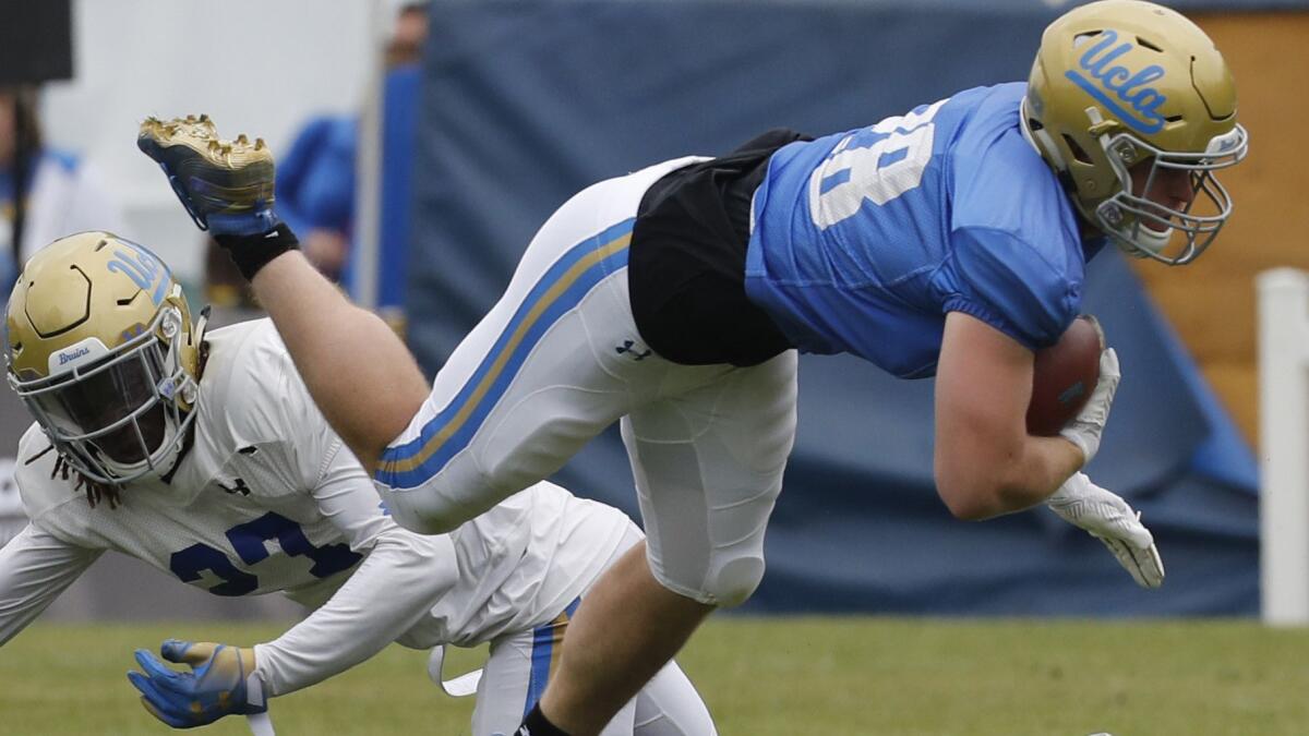 UCLA running back Cole Kinder gets tripped up by Patrick Jolly during the annual spring game at Drake Stadium in Westwood.