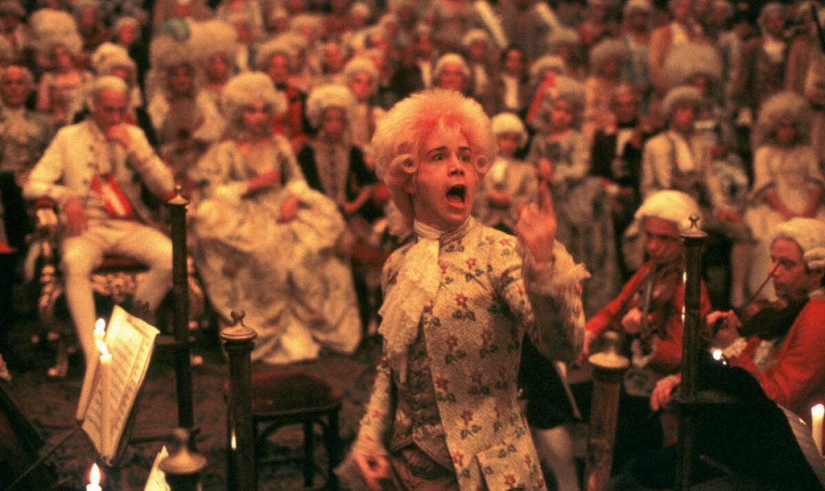A man in a pink wig conducts an orchestra.