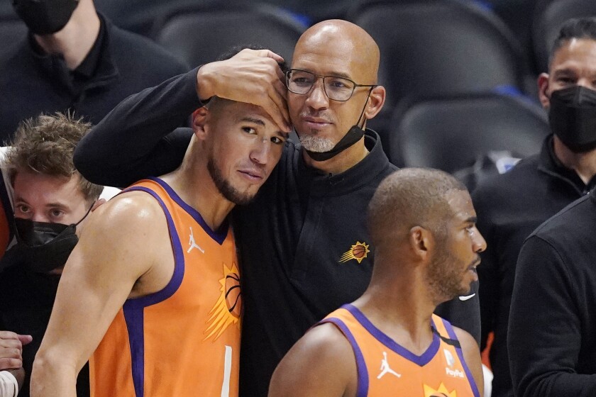 Phoenix Suns coach Monty Williams hugs Devin Booker as Chris Paul stands nearby.