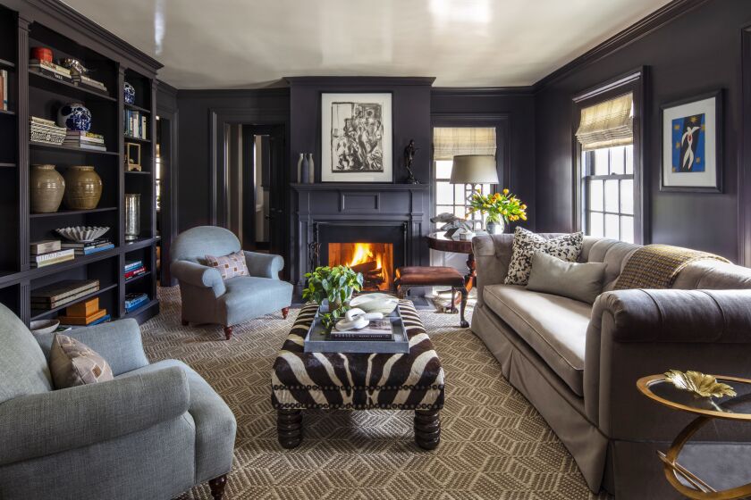 A redesigned living room has the fireplace mantel painted the same color as the walls, a dark aubergine.