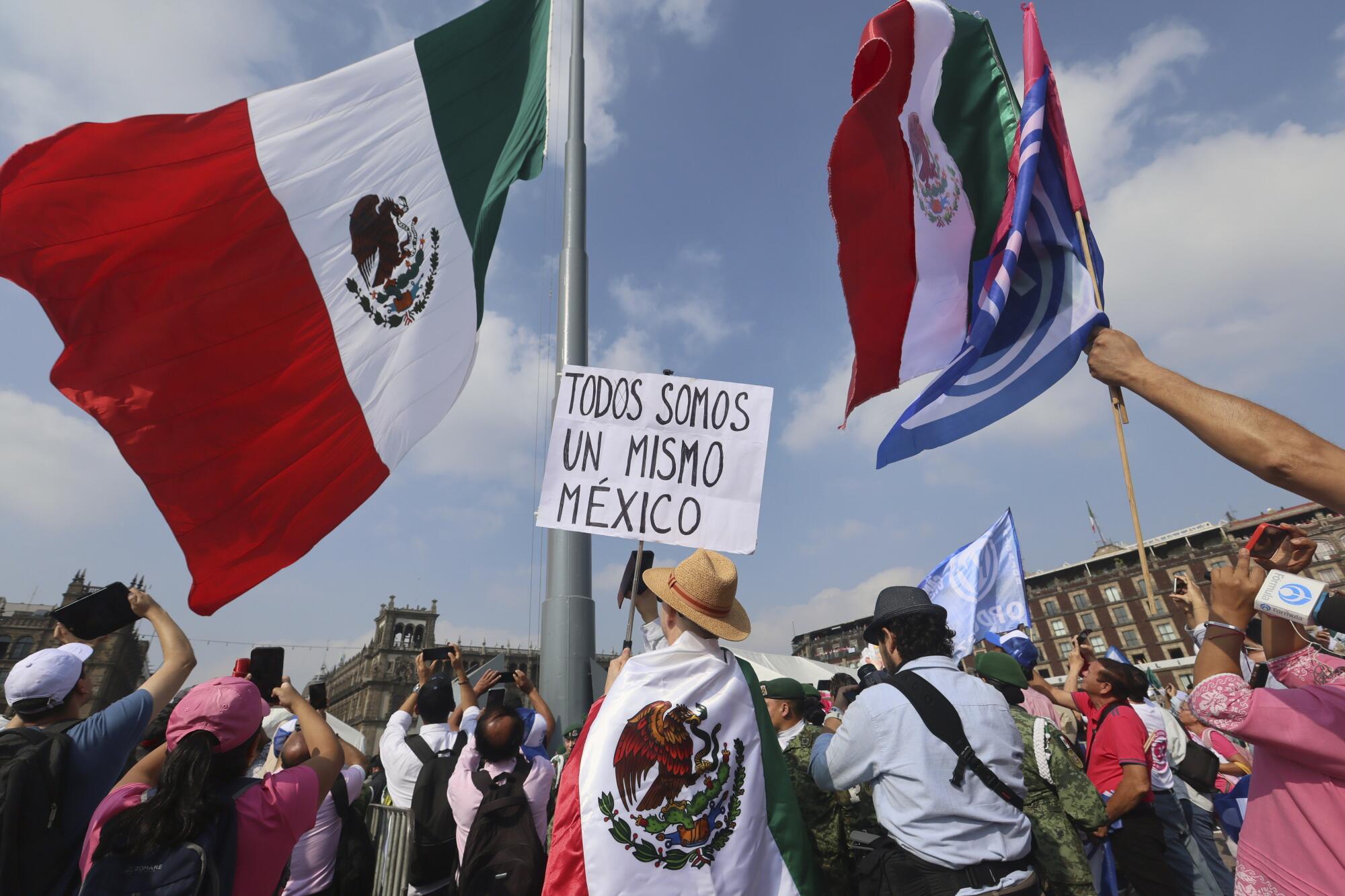 A person holds a sign that reads, "We are all the same Mexico," at an opposition rally. 