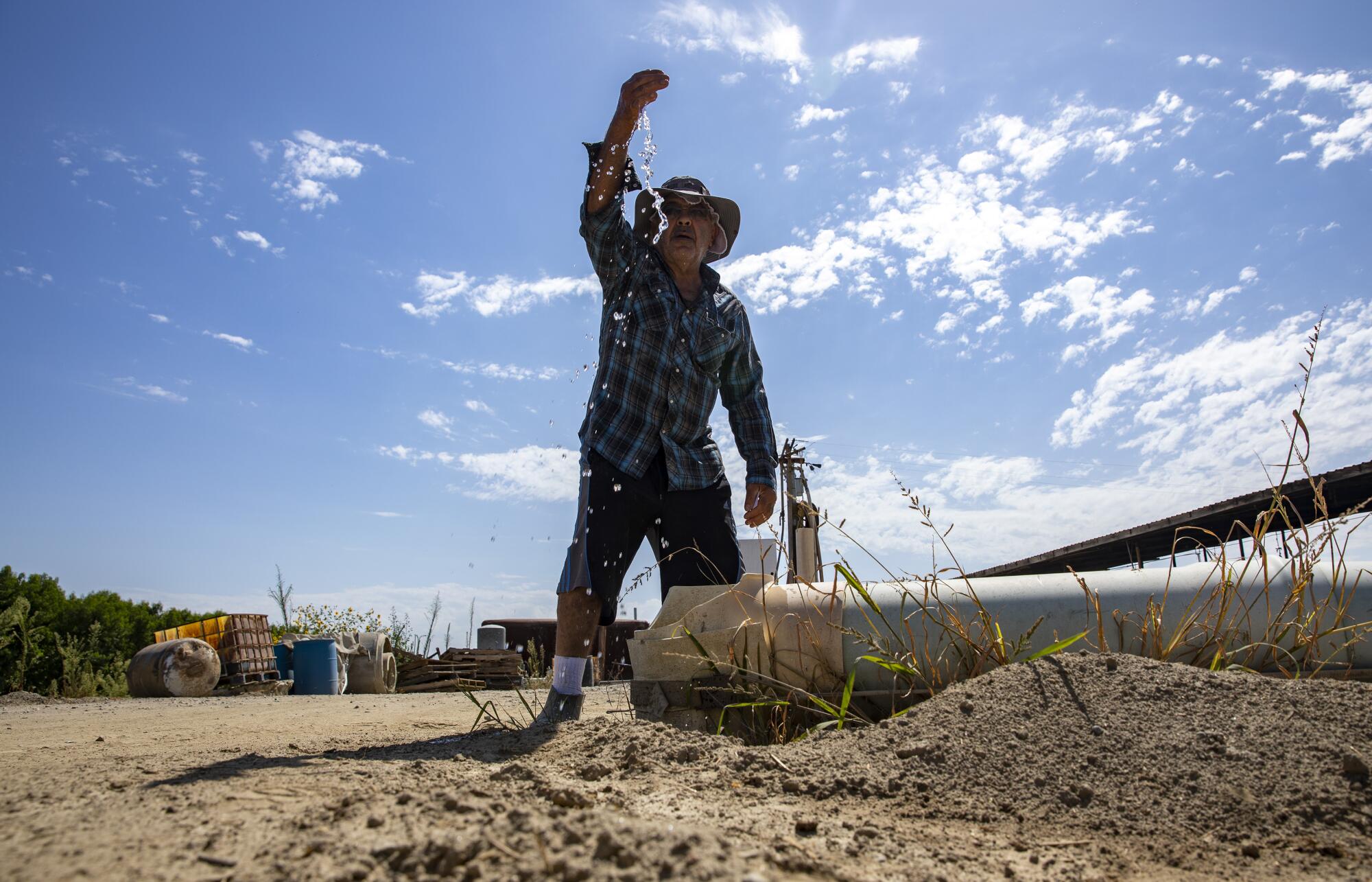 A man lets water pour from a hand as he holds it over his head.