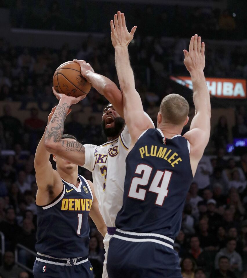 Lakers forward Anthony Davis tries to put up a shot between Denver Nuggets' Michael Porter Jr. and Mason Plumlee.