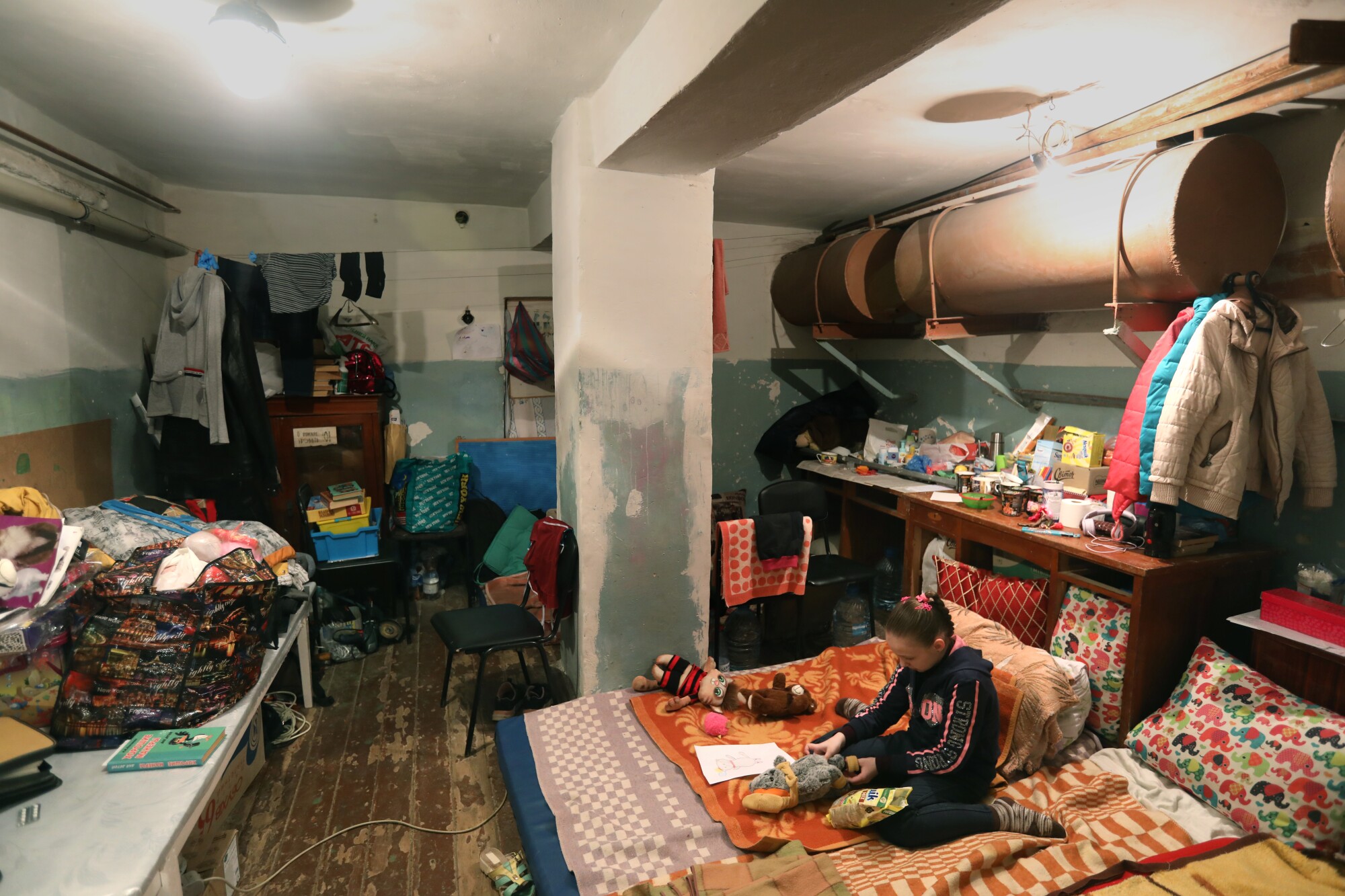 A girl plays with her stuffed animal in the basement of a school in Severodonetsk.