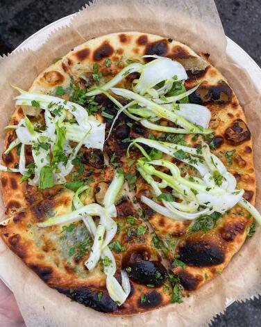 An overhead photo of a round focaccia di Recco from pop-up Glad, topped with shaved fennel