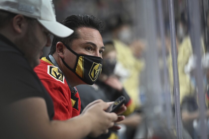 Oscar De La Hoya wears a face mask while watching a hockey game