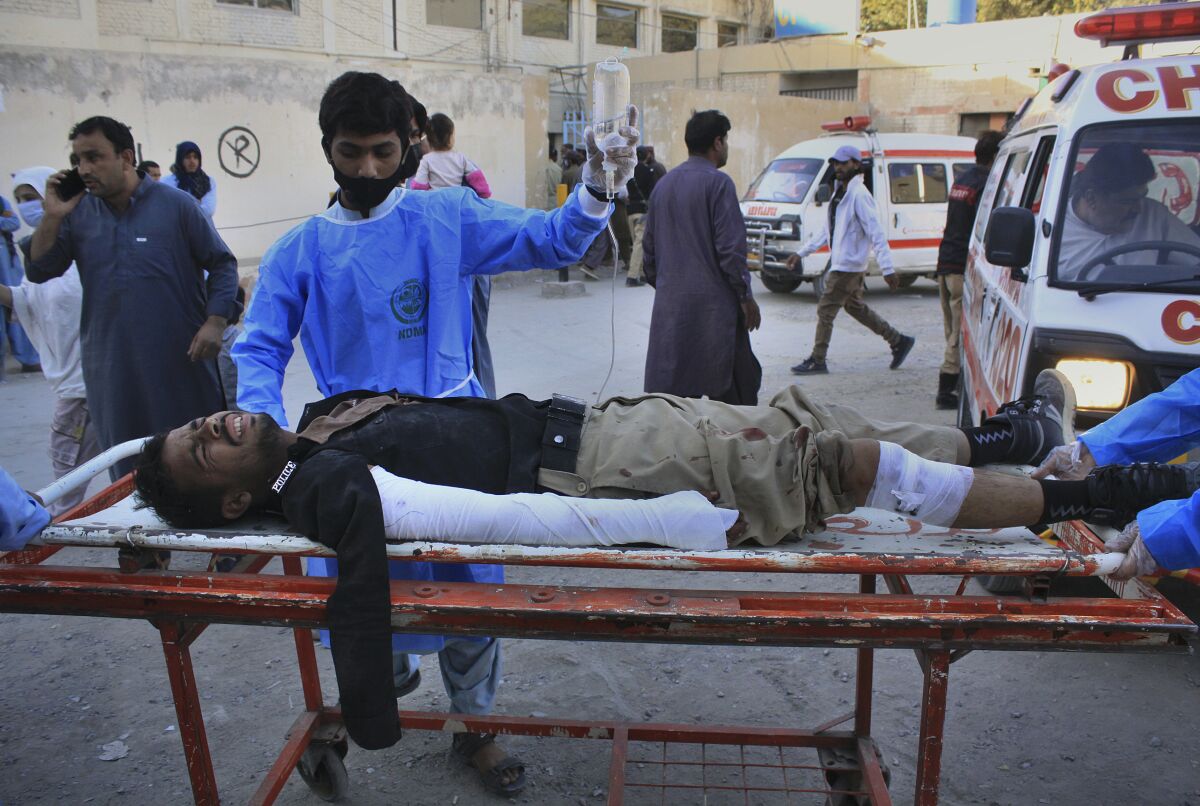 Paramedics transport a police officer who was injured in a deadly bomb blast, following his initial treatment at a hospital, in Quetta, Pakistan, Monday, Oct. 18, 2021. A roadside bomb exploded near a police bus parked outside the Baluchistan University in Quetta, the capital of Baluchistan province in southwest Pakistan, killing and wounding people, a provincial home minister said. (AP Photo/Arshad Butt)