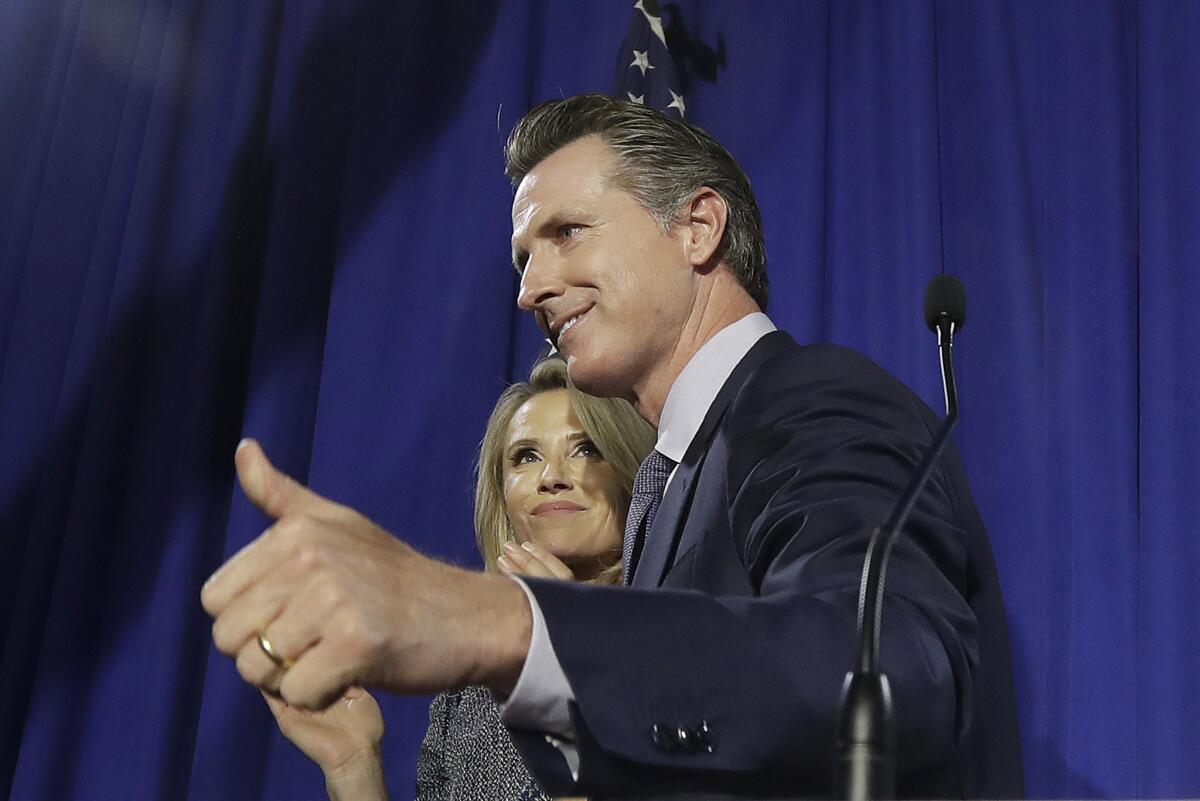 El demócrata Gavin Newsom junto a su esposa Jennifer Siebel Newsom después de hablar en el festejo nocturno de su campaña gubernamental en San Francisco, el martes 5 de junio de 2018. (AP Photo / Jeff Chiu)