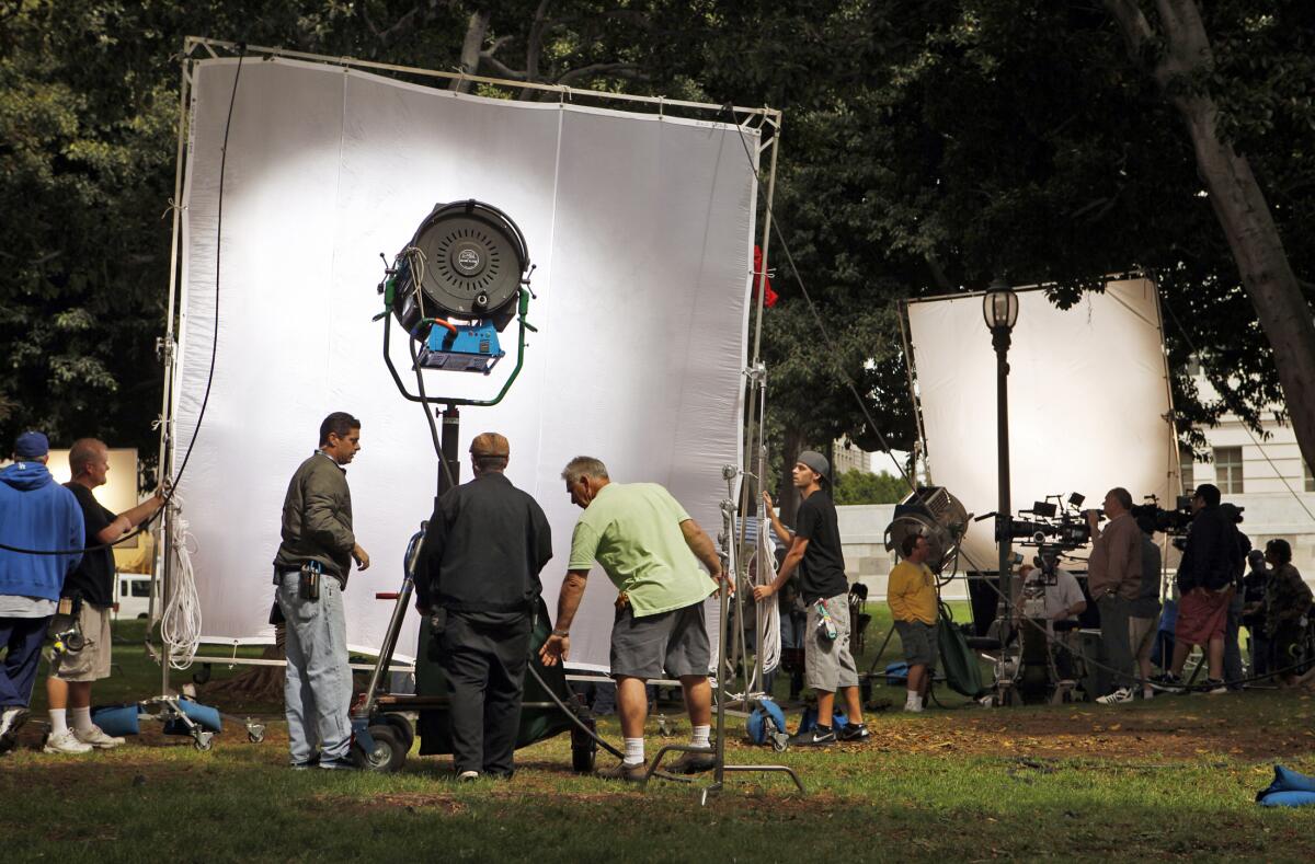 A film crew sets up lights and cameras for shooting a scene. 