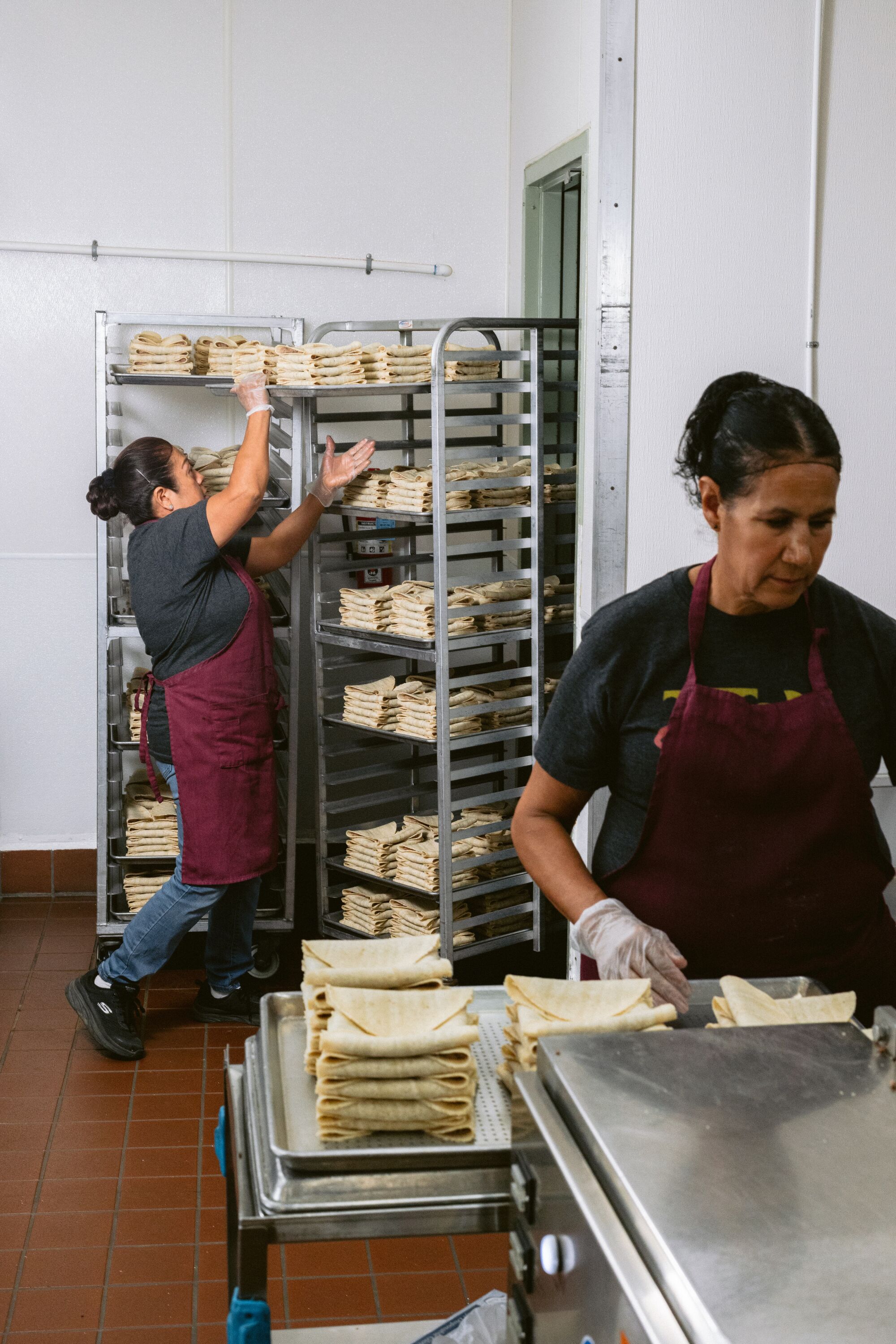 Tito's Tacos employees stack and store tacos.