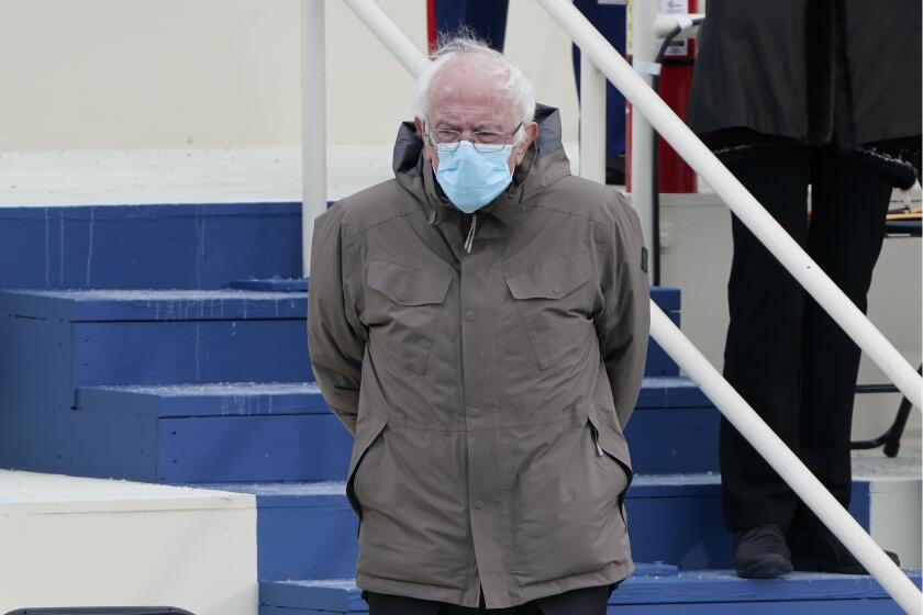 Sen. Bernie Sanders standing in a coat and face mask