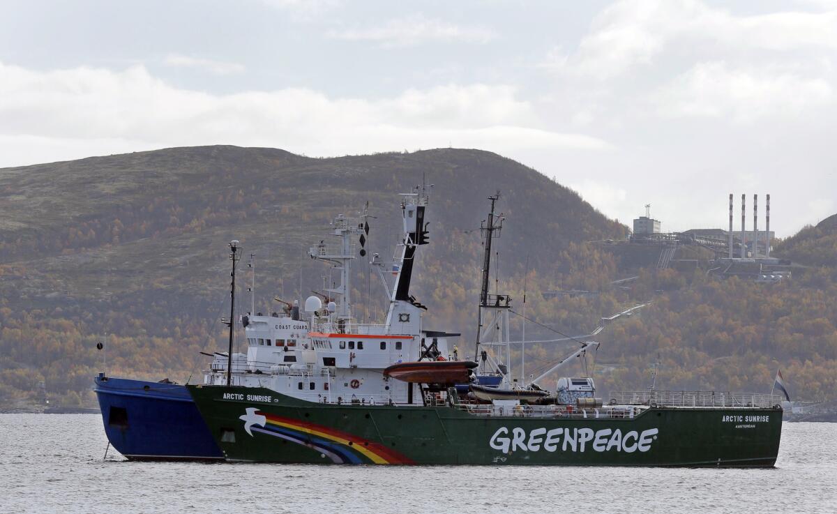 A blue Russian coast guard boat escorts Greenpeace's Arctic Sunrise.