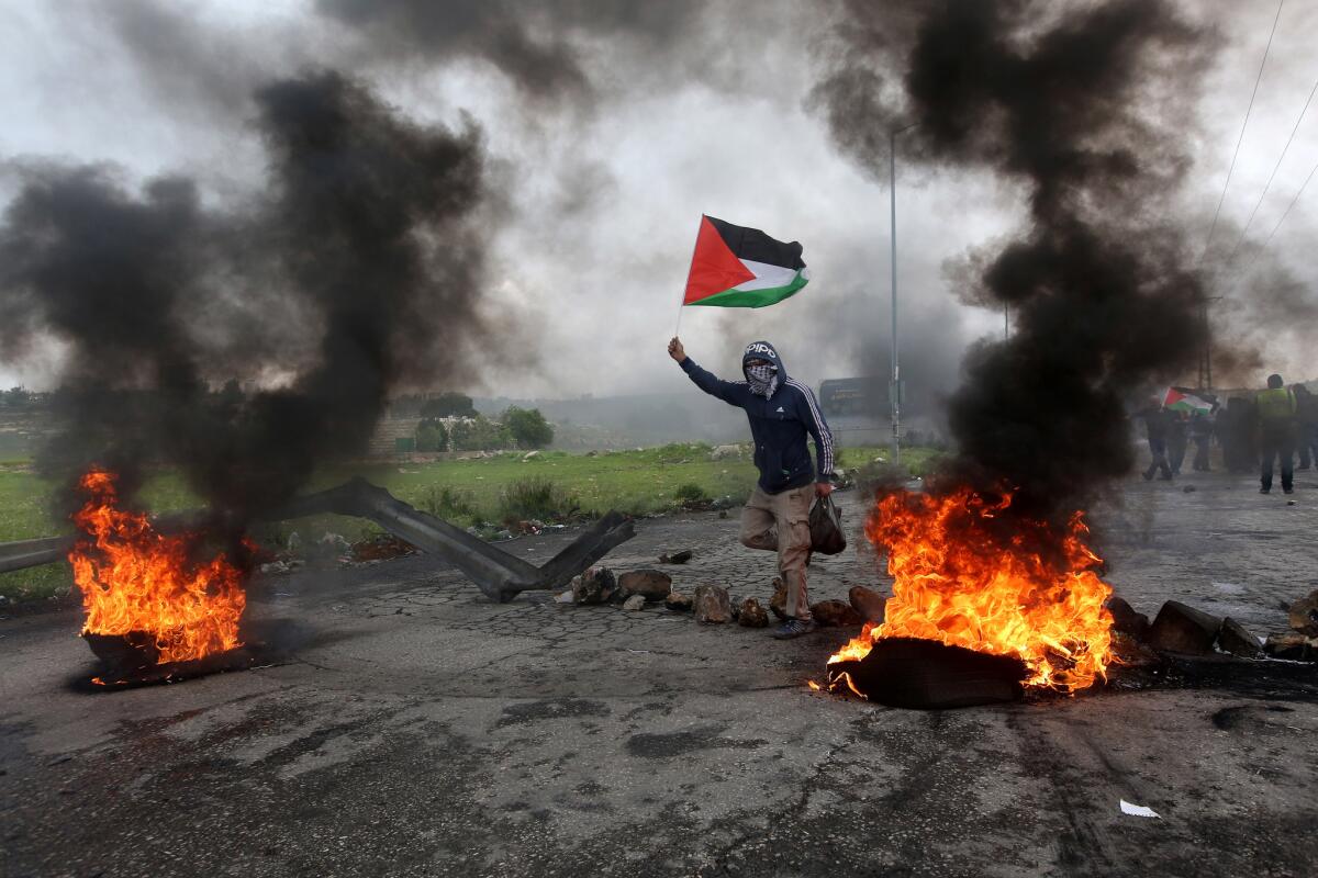 A protester waves the Palestinian flag during clashes marking Land Day in the West Bank city of Ramallah.